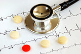 A stethoscope on the top of the EKG chart with pills concept of modern medicine