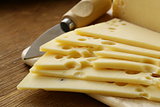 Maasdam cheese sliced ​​on a wooden board