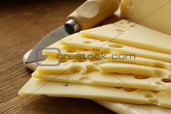 Maasdam cheese sliced ​​on a wooden board