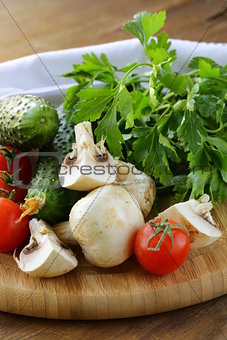 tomatoes, cucumbers, mushrooms and parsley on a cutting board