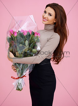 Happy brown haired young woman holding flowers