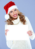 Smiling woman in Santa hat holding blank board