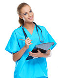 Cute nurse looking at the camera and smiling with writingpad