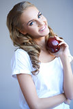Head shot of woman holding red apple against grey