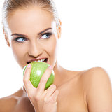 Woman tries to bite a fresh green apple