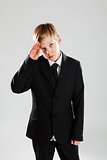 Serious young boy in black suit saluting