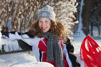 Girl in winter cloths with red sledge