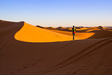 Woman walking on top of a sand dune