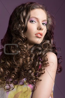 pretty brunette with curly hair looks in to the lens