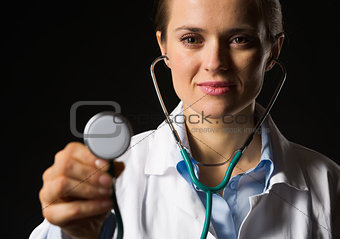Medical doctor woman using stethoscope isolated on black