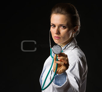 Confident medical doctor woman using stethoscope isolated on bla