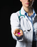 Closeup on medical doctor woman showing pills on black backgroun