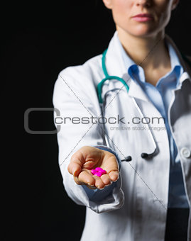 Closeup on medical doctor woman showing pills on black backgroun
