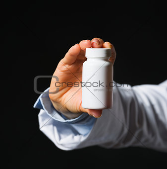 Closeup on hand with medicine bottle isolated on black