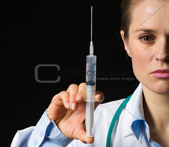 Closeup on medical doctor woman holding syringe isolated on blac