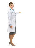 Full length portrait of medical doctor woman pointing on copy sp