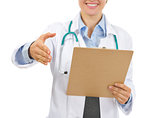 Closeup on medical doctor with clipboard streching hand for hand