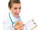 Angry medical doctor woman with clipboard pointing in camera