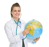 Happy medical doctor woman listening globe with stethoscope