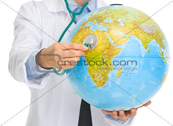Closeup on medical doctor woman listening globe with stethoscope