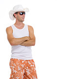 Happy young man in sunglasses and hat looking on copy space
