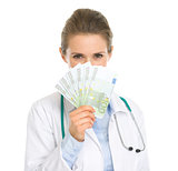 Medical doctor woman hiding behind fan of euros