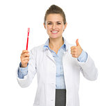 Smiling medical doctor woman showing toothbrush and thumbs up