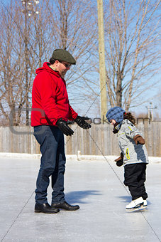Father teaching daughter how to ice skate