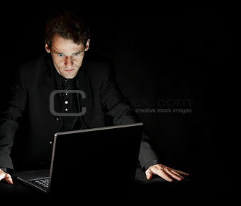Hacker with laptop in dark room