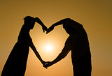 Sillhouette loving couple at sunset with heart