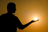 Young man holding the sun on his hand