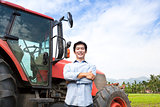 happy middle aged asian farmer with old tractor
