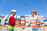two happy workers handshaking before transportation containers
