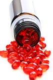 Red capsules with vitamins spilled from the bottle.