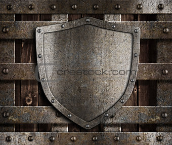 aged metal shield on wooden medieval gates