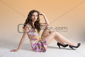 wavy brunette sitting on the floor looks in to the lens
