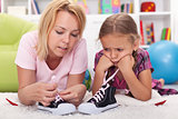 Mother teaching little girl to tie her shoes