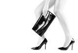 Beautiful slender womanish feet in black shoes and mini bag