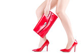 Beautiful slender womanish feet in red shoes and mini bag