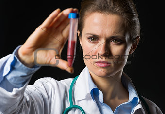 Medical doctor woman looking on test tube with blood isolated on