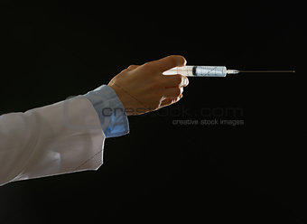 Closeup on hand of medical doctor with syringe isolated on black