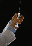 Closeup on hands of medical doctor knocking on syringe isolated 