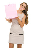 Portrait of happy young woman showing pink shopping bag