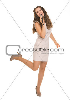 Full length portrait of happy young woman singing with microphon