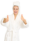 Smiling young woman in bathrobe showing thumbs up