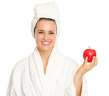 Smiling young woman in bathrobe with apple