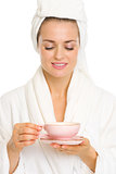Happy young woman in bathrobe enjoying cup of tea