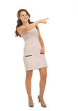 Full length portrait of happy young woman pointing on copy space