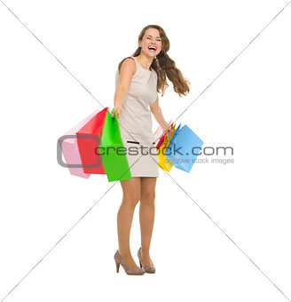 Full length portrait of happy young woman spinning shopping bags