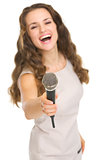 Happy young woman stretching microphone in camera